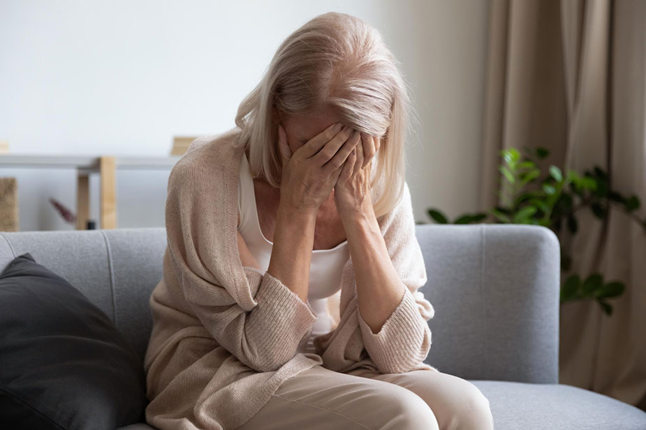 Žena sedi na kauči - pokrila je lice rukama jer je muče promene raspoloženja u menopauzi