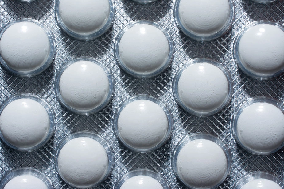 Krupni plan belih tableta u blister pakovanju, ilustracija hormonske supstitucione terapije.