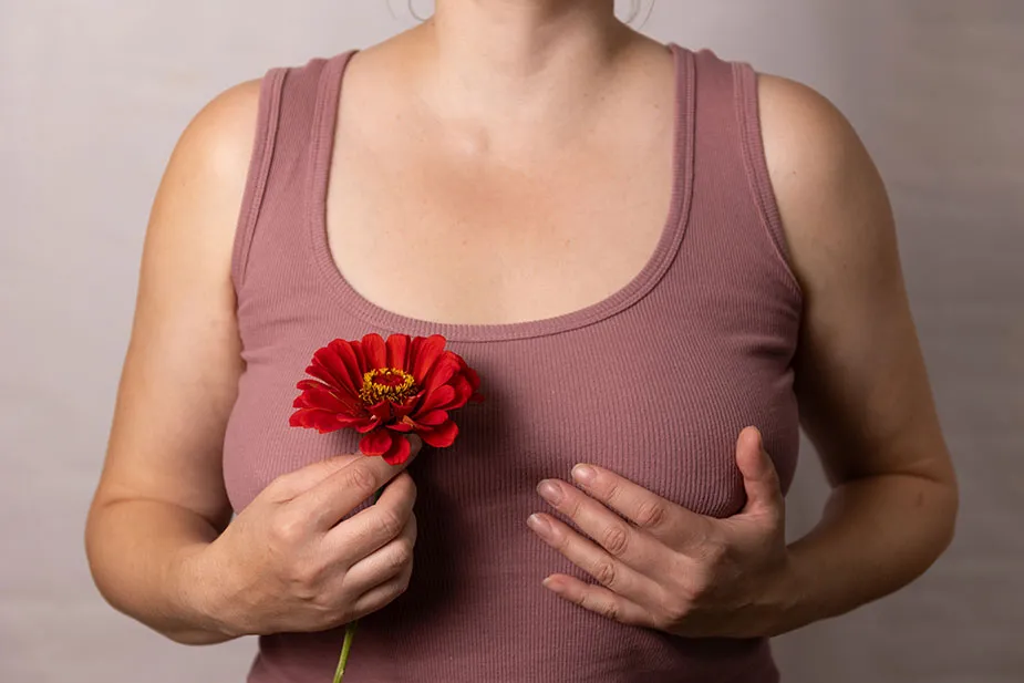 Žena drži cveće dok obavlja samopregled dojki